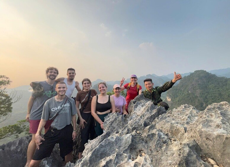 A group of people standing on a rocky outcrop with a mountainous landscape in the background. 1