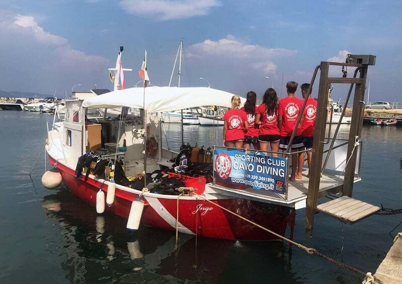 A red and white boat docked at a marina with a sign for a sporting club diving. 3