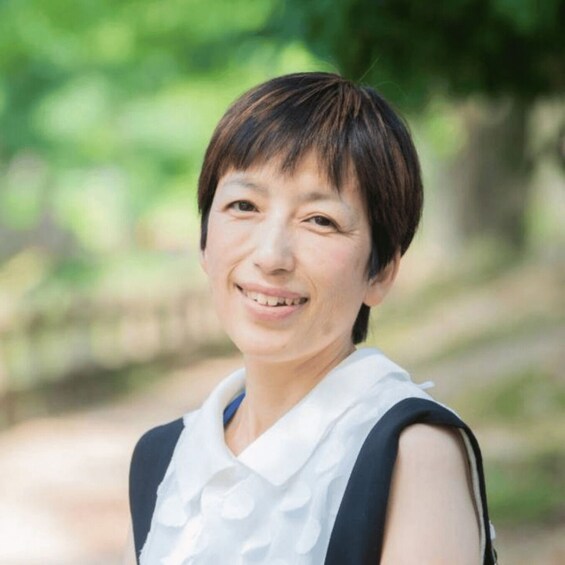 A person standing outdoors with greenery in the background. 1