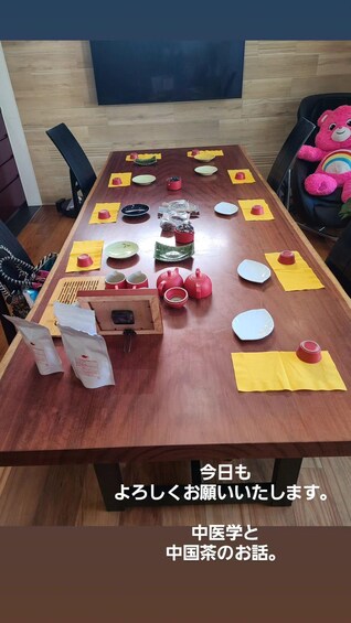 A wooden dining table with various dishes, cups, and a pink stuffed toy. 2