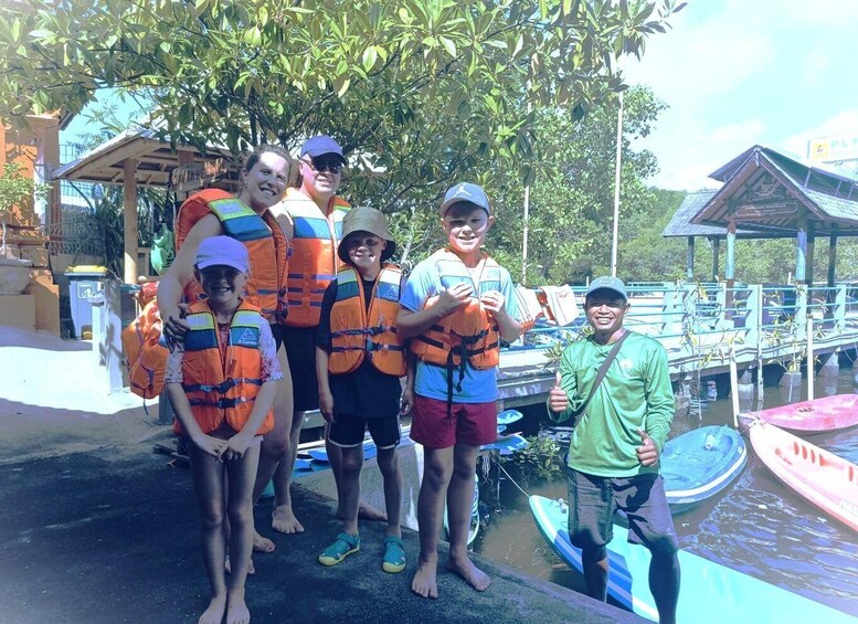 A group of people wearing life jackets near a dock with boats. 3