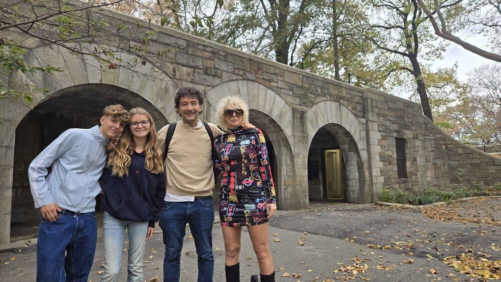 A group of people standing in front of a stone bridge with arched passageways. 2