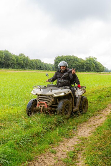 A person on a quad bike in a green field with trees in the background. 2