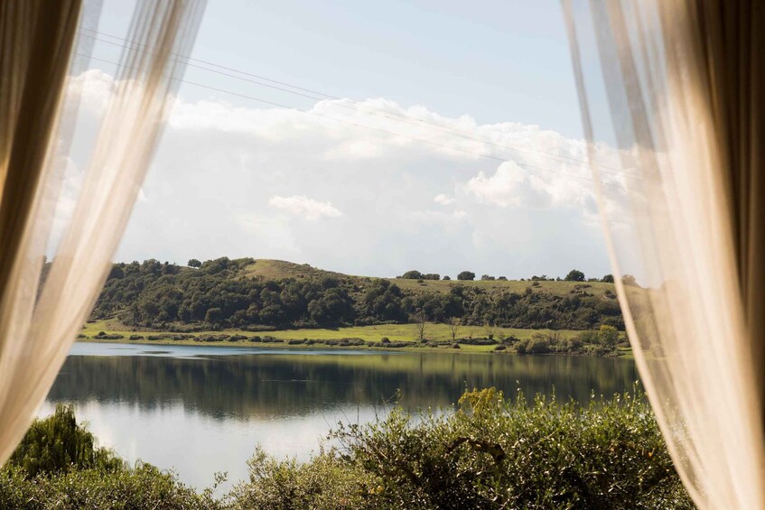 A lake with hills in the background, viewed through sheer curtains. 3