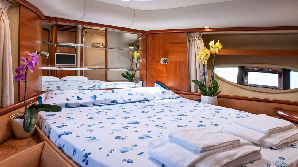 A stateroom with a bed, wooden paneling, a window, and a potted plant. 4