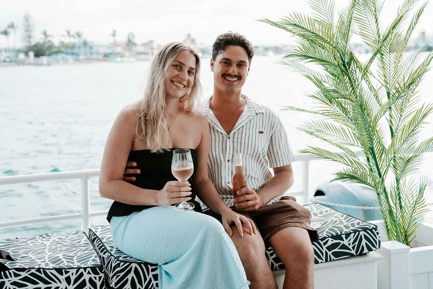 Two people sitting on a boat with a view of the water and palm trees. 2