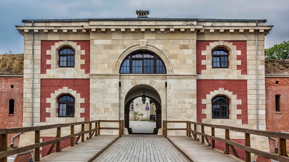 A stone building with arched windows and a wooden bridge leading to it. 5