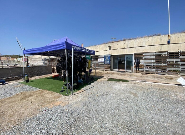 A blue tent with a website URL, a fenced area with sports equipment, and a building with a sign. 5