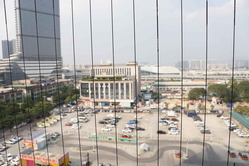 A cityscape with a large parking lot, a prominent building with columns, and modern high-rise buildings in the background. 1