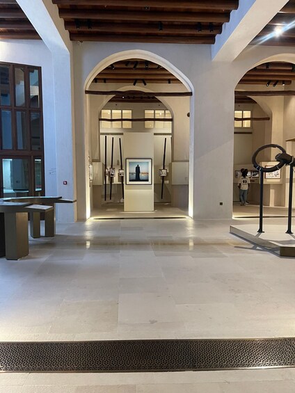 An art gallery with a central viewing area, wooden beams, and a patterned floor. 5