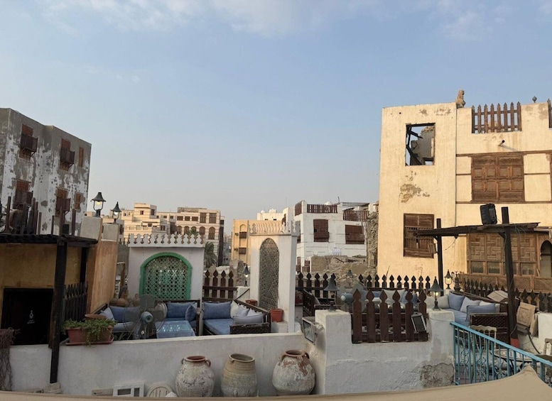 A rooftop with outdoor furniture, a green gate, and traditional buildings with wooden shutters. 2