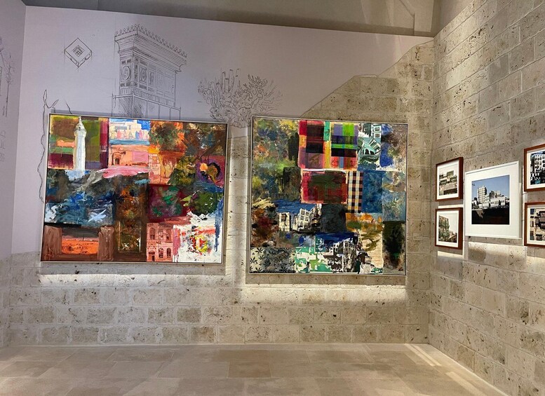 Two large abstract paintings with a collage of images in a gallery with stone walls and framed photographs on the right. 5