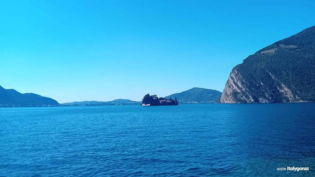 A calm sea with a small island in the distance, surrounded by steep cliffs. 3