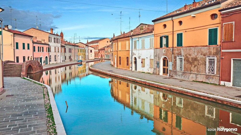 A canal with buildings on either side, a bridge, and a clear sky. 3