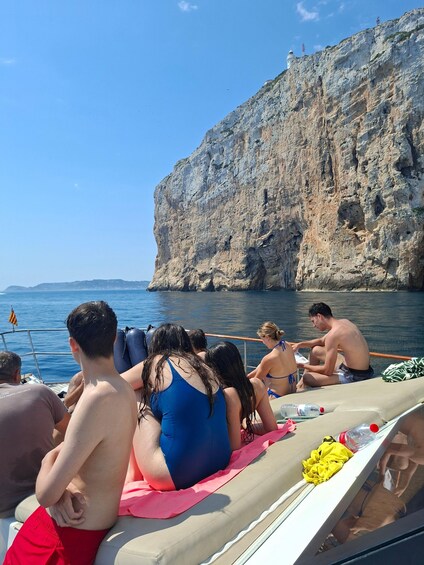 People on a boat near a rocky cliff by the sea. 2