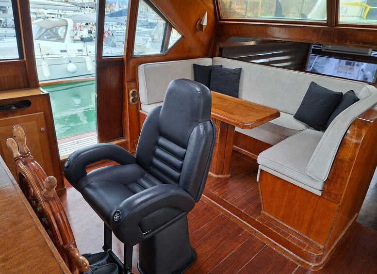 A boat interior with a leather captain's chair, a cushioned sofa, and a wooden table. 5