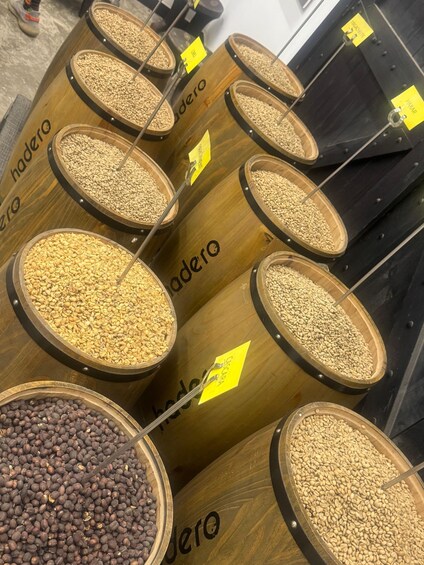 Multiple wooden barrels labeled 'hadero' containing various grains and beans. 5