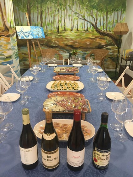 A dining table set with wine bottles, plates of food, and glasses. 1