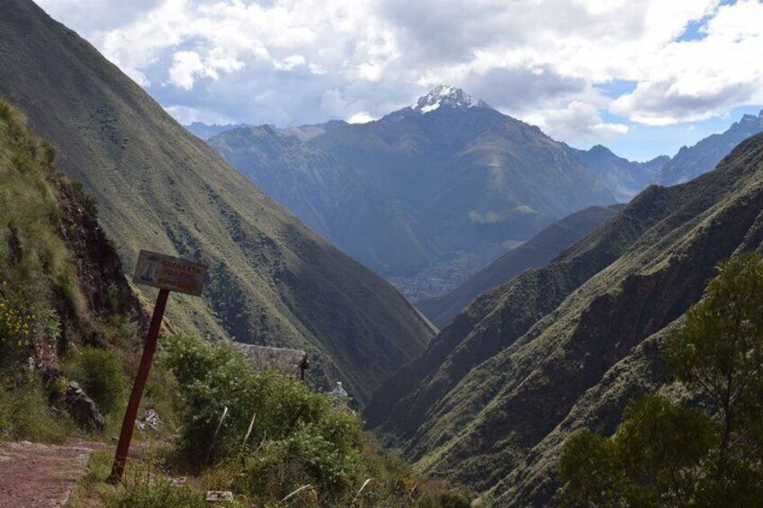 A mountainous landscape with a signpost and a trail. 5