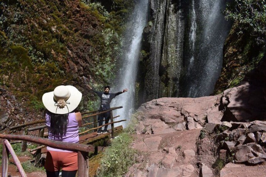 A waterfall with a person standing on a wooden bridge. 4