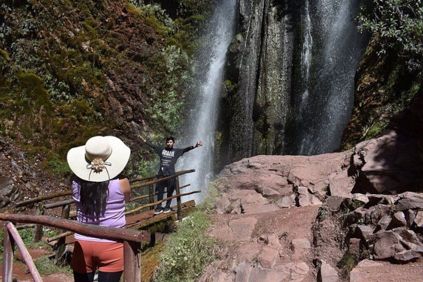 A waterfall with a person standing on a wooden platform. 4