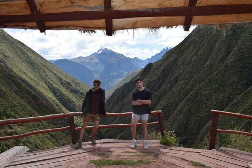 Two people standing on a wooden platform with a mountain backdrop. 3