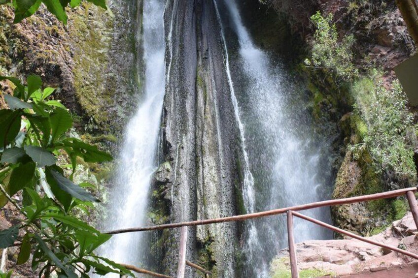 A waterfall cascading down a rocky cliff surrounded by greenery. 2