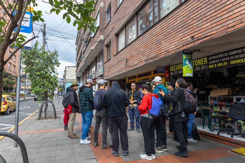 A group of people standing on a sidewalk in an urban area with brick buildings and a yellow taxi on the street. 3