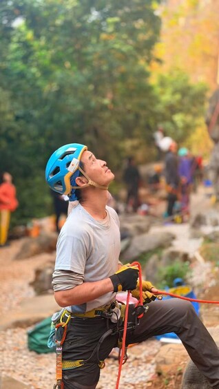 A person engaged in rock climbing, equipped with a helmet, harness, and climbing gear. 5
