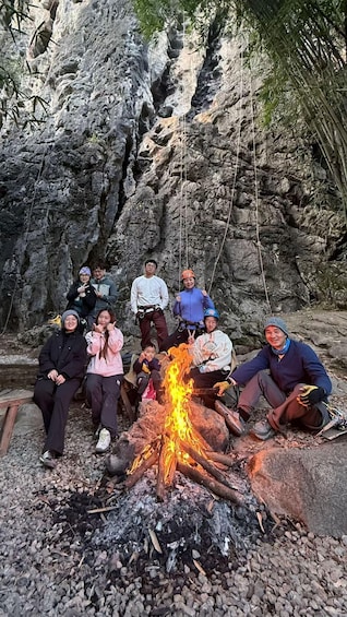 A group of people around a campfire in a rocky outdoor setting. 2