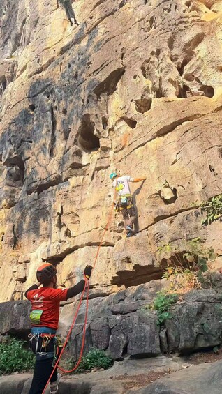 A person rappelling down a rocky cliff with a rope. 3