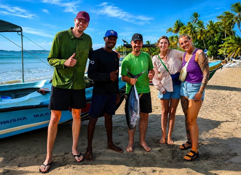 A group of people on a beach with a boat and palm trees in the background. 2