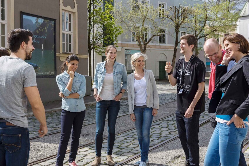 A group of people standing on a cobblestone street with buildings and trees in the background. 4