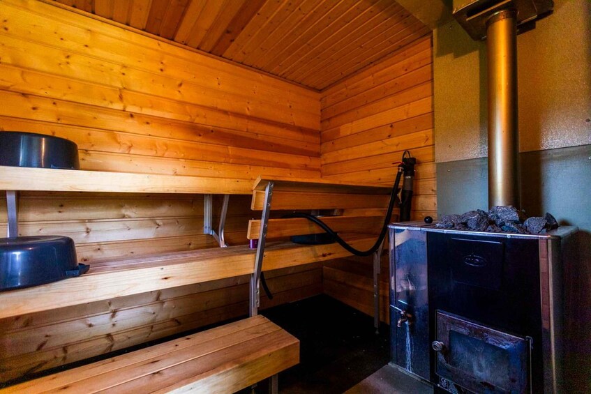 A sauna with wooden benches and a wood-burning stove. 3