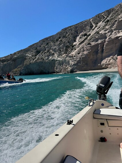 A boat on a turquoise sea with rocky cliffs in the background. 4