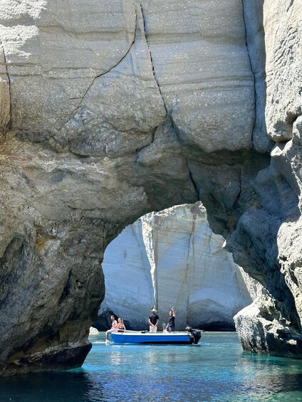 A boat passing through a natural rock arch in a body of water. 2