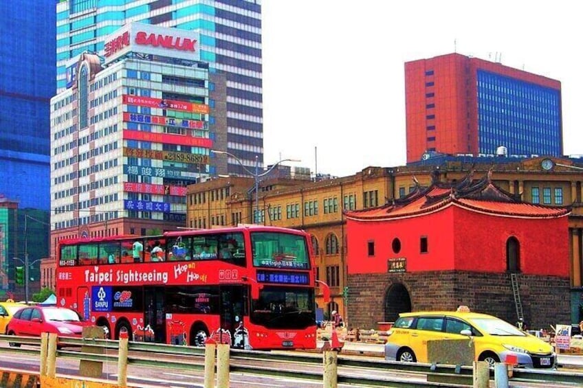 A red double-decker bus, a yellow taxi, and a traditional red building with a clock tower. 3