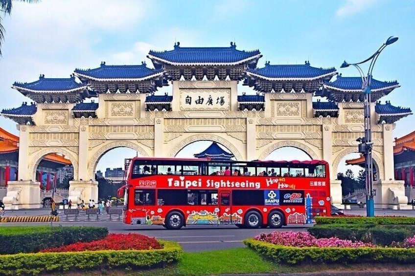A red double-decker bus labeled 'Taipei Sightseeing' in front of a traditional Chinese gate. 5