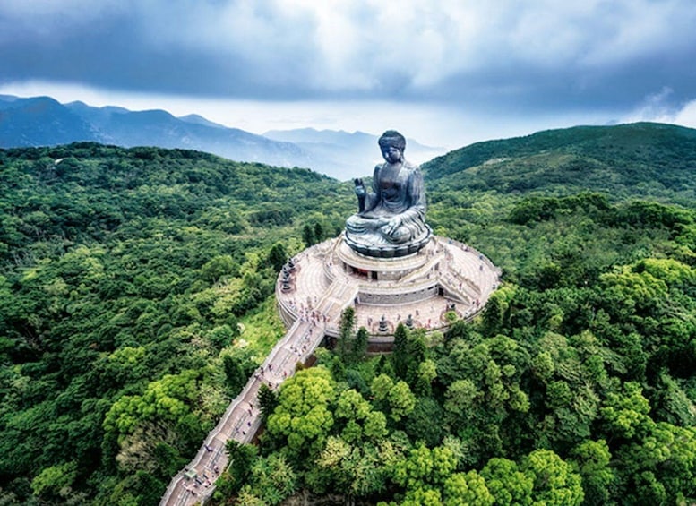 Suuri Buddha-patsas, jonka ympärillä on vehreää kasvillisuutta ja taustalla kohoavat vuoret. 4