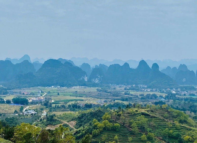 A landscape with terraced fields, a small settlement, and a range of karst limestone hills. 2