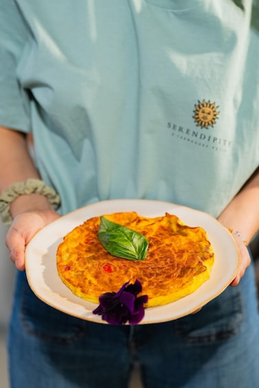 A person holding a plate with a food item, wearing a light blue shirt with a logo. 5