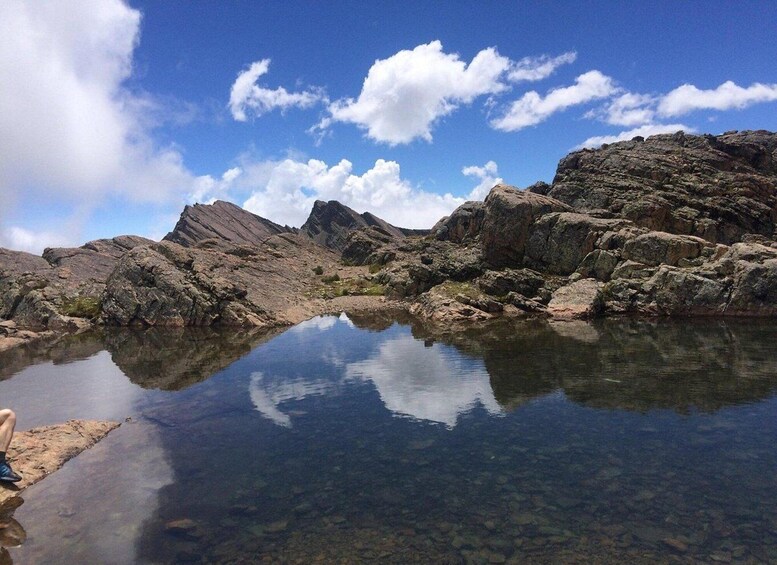 A rocky landscape with a clear water body reflecting the sky and mountains. 3