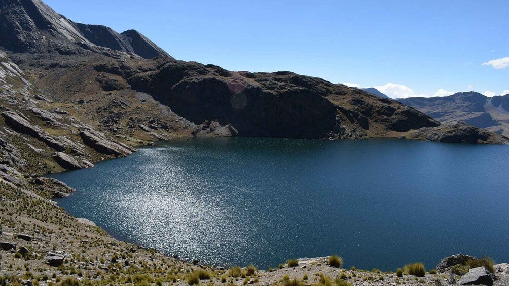 A lake surrounded by rugged mountains under a clear sky. 1