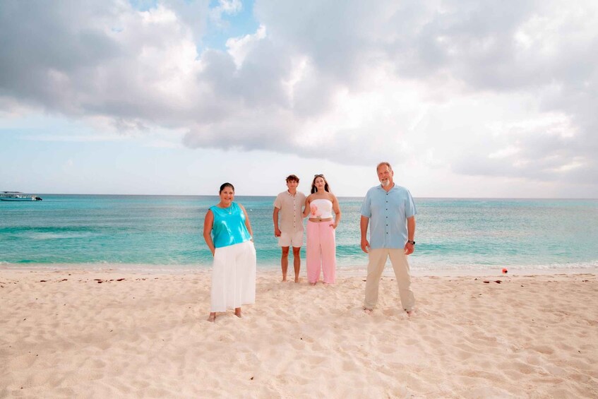 A group of people standing on a sandy beach with a calm sea and a partly cloudy sky in the background. 3