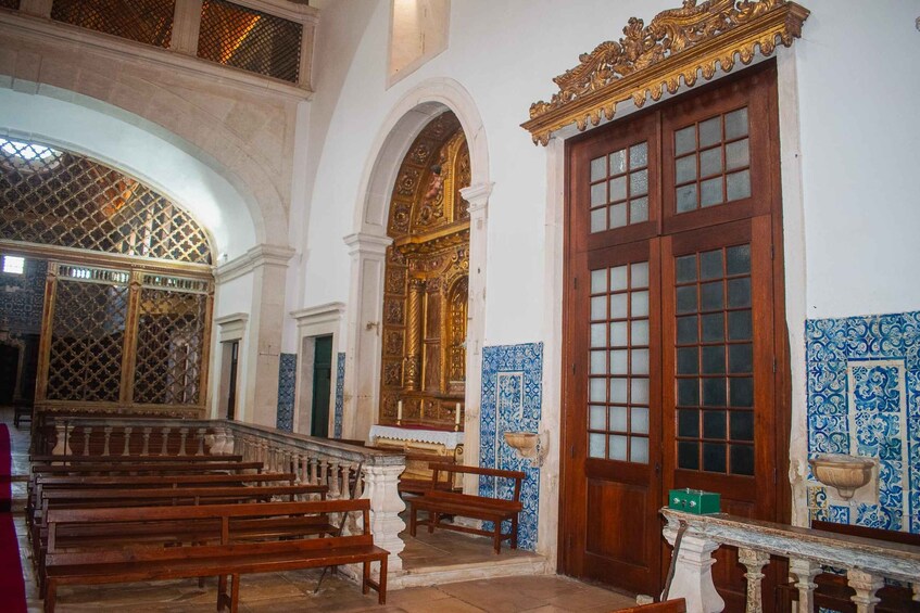 An ornate church interior with wooden benches, a large wooden door, and blue and white patterned tiles. 5