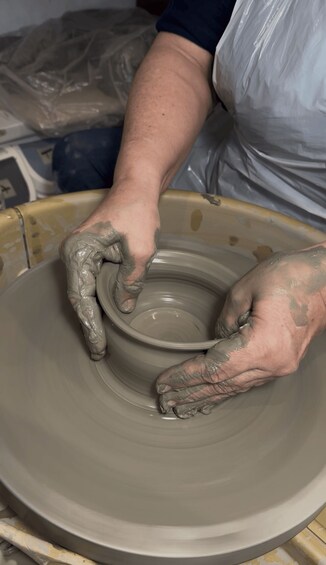 Hands shaping a clay pot on a spinning wheel. 3