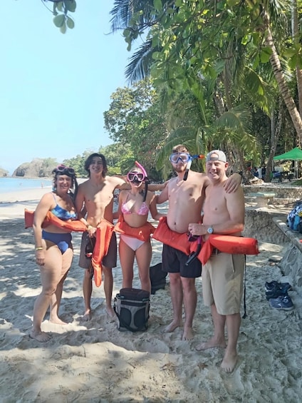 A group of people on a sandy beach with palm trees and a clear sky. 2