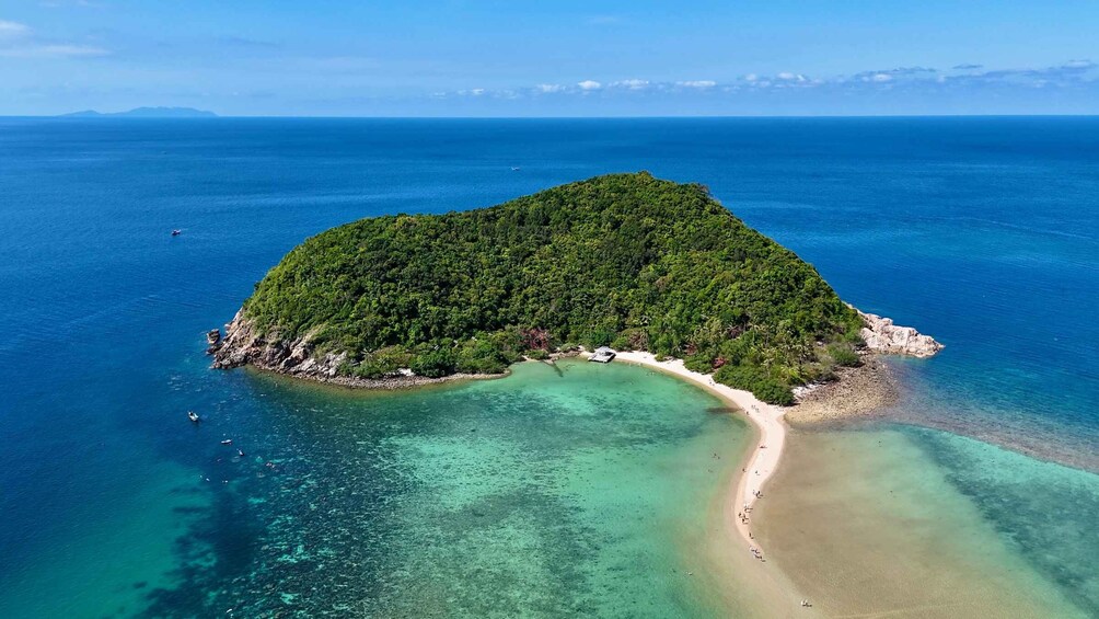 An aerial view of a lush, green island surrounded by clear turquoise waters. 1