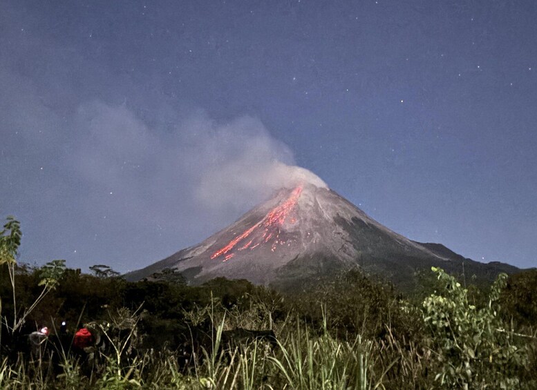 Un vulcano con lava che scorre lungo il suo fianco, di notte. 1