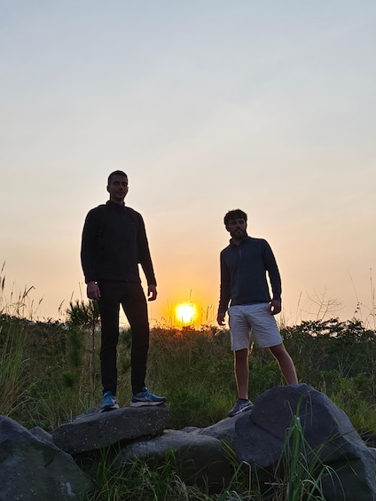 Due persone in piedi su delle rocce, con il tramonto sullo sfondo. 3